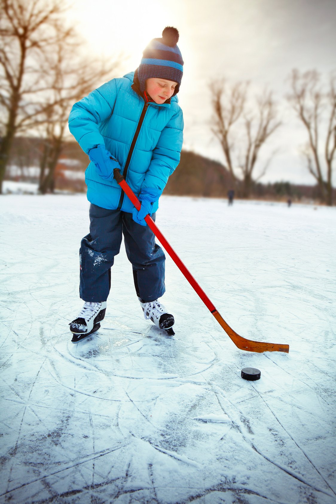 Little boy training ice hockey on the pond